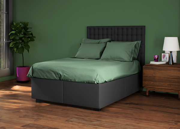 Dark bed with headboard and green bedding, wooden bedside table in styled bedroom.