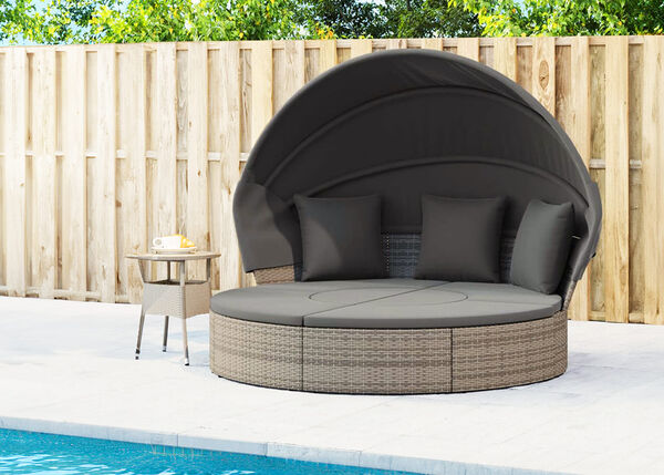 Round rattan lounge bed with gray cushions, dark gray canopy, and a side table, by the pool. Click to see the products in the collection.
