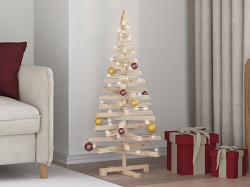 Minimal wooden Christmas tree with lights and ornaments beside wrapped gifts. Click to see the products in the collection.