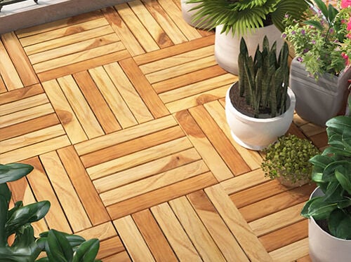 Wood decking tiles on a balcony surrounded by green potted plants. Click to see the products in the collection.