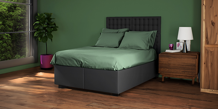 Dark bed with headboard and green bedding, wooden bedside table in styled bedroom. Click to see the products in the collection. 